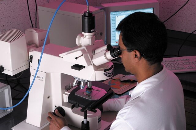 Research laboratory Research scientist analysing a sample under a microscope, illustrating contract research and biopharmaceutical development