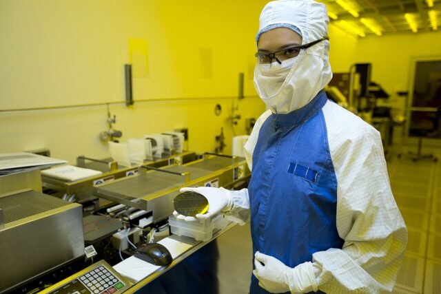 Researcher holding a silicon wafer in a semiconductor fabrication facility