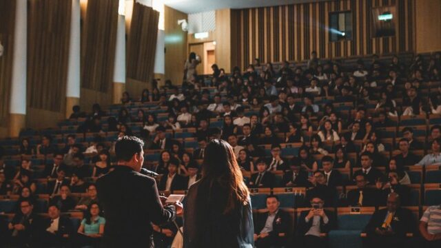 Delegates seated in a conference auditorium listening to speakers