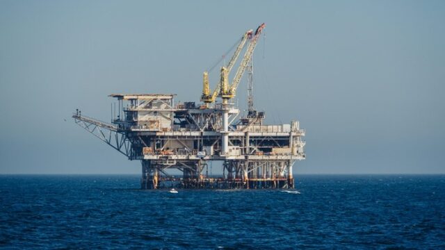 Offshore oil and gas platform standing in open blue sea under clear daylight, a generic illustration for an offshore jack-up drilling contract report.