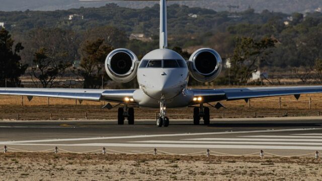 A white business jet taxiing at an airport in daylight